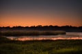 The banks of the Okavango River in Botswana, under the orange glow of sunrise on this stretch of river preceding the Okavango Del