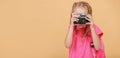 banner of adorable child girl takes picture with vintage retro camera. Little girl photographer on yellow background Royalty Free Stock Photo
