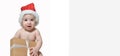 BannerAdorable newborn baby wearing Santa Claus hat, Christmas, New Year holding a gift with a white ribbon. child on an isolated Royalty Free Stock Photo