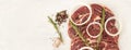 Banner beef, onion rings, mixed pepper, pink salt, thyme, rosemary. Raw beef meat with spices on a white stone background Royalty Free Stock Photo