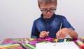 Banner boy in a blue shirt and glasses sits at a table on a white background Creative activities hobby drawing