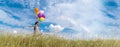 Banner Cheerful cute girl holding balloons running green meadow white cloud and blue sky with happiness. Panorama Hands holding