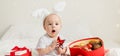 Banner Christmas Baby in Santa Hat Child playing with baubles, copy space. Present Gift Box over Holiday Lights Royalty Free Stock Photo