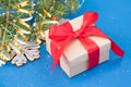 Banner with Christmas present box with red ribbon bow over blue background with Christmas tree branches Royalty Free Stock Photo