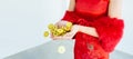 Banner close up on golden coins on hands of a woman wearing red dress to celebrate Chinese New Year, presenting about wealthy and