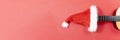 Banner with copy space Christmas guitar on a red background with Christmas Hat. An invitation to a New Year& x27;s musical Royalty Free Stock Photo