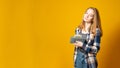 Banner copy space. Cute young girl with gray wallet full of money dollars on a yellow background Royalty Free Stock Photo