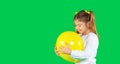 Banner. Cute preschool blonde girl with two pigtails hugs a illuminating color balloon. Green background and side space