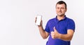 Banner. Deaf senior man shows thumb up while holding a mobile phone, white screen to the camera. White background and Royalty Free Stock Photo