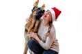 Banner. Dog with deer antlers kisses girl in Santa hat. Woman and pet celebrates new year, Christmas. Greeting card with German