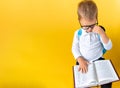 Banner Funny Preschool Child Boy in Big Glasses Reads Book on Yellow Background Copy Space. Happy Smiling Kid Go Back to Royalty Free Stock Photo