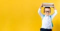 Banner Funny Preschool Child Boy in Glasses with Book on Head and Bag on Yellow Background Copy Space. Happy smiling kid Royalty Free Stock Photo