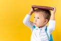 Banner Funny Preschool Child Boy 3-4 years with Book on Head and Bag on Yellow Background Copy Space. Happy Smiling Kid Royalty Free Stock Photo