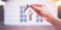 Banner with hand, house key close-up on bokeh background of building for advertising of purchase,rental apartment,house