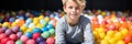 Banner Happy boy in fun childrens shopping center playing in a dry pool with colorful balls Royalty Free Stock Photo