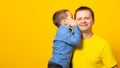 Banner. Happy father`s day! Cute father and son hugging on yellow background. Portrait of a dad with a baby boy