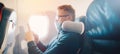 Banner Hipster man in protection mask is watching video on mobile phone, reading online book traveling on airplane Royalty Free Stock Photo