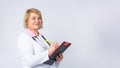 Banner- long format. An attractive senior female doctor in white coat with sthetoscope, writes analysis on black clipboard with