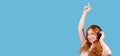 Banner,long format over blue background. Enthusiastic caucasian woman listening music by headphones, dancing Royalty Free Stock Photo