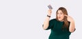 Banner, long format. Shocked young plus size body positive woman 30s standing pointing index finger on credit bank card Royalty Free Stock Photo