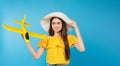 Banner, long format. Travel concept. Young beautiful bright girl in a big summer hat with a illuminating toy plane in her hands on Royalty Free Stock Photo