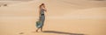 BANNER, LONG FORMAT Young beautiful woman traveling in the desert. Sandy dunes and blue sky on sunny summer day. Travel Royalty Free Stock Photo