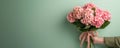banner,a man\'s hand in a green shirt holding a large bouquet of pink hydrangeas with a beige ribbon, on a green background,