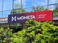 Banner of Moneta Money bank behind the green bush