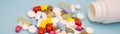 Banner multicolored pills fall out of a white bottle on a blue background Royalty Free Stock Photo
