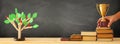 banner of open book, gold trophy and wooden tree puzzle over blackboard background. education and knowledge concept.