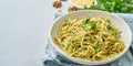 Banner with pesto pasta, bavette with walnuts, parsley, garlic, nuts, olive oil. Side view, long side, copy space, blue background