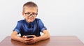 Banner Portrait of smiling boy with glasses using mobile phone on school Desk on white background Modern mobile and communications