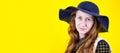 Banner Portrait of a young beautiful red-haired girl with long loose hair, gently looking at the camera. On a yellow Royalty Free Stock Photo