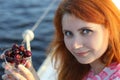 Banner with a portrait of a young red-haired woman and ripe cherries on a blue sea background Royalty Free Stock Photo