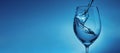 Banner with pouring water into a transparent glass for wine close-up. light blue background with water splashes and copy space Royalty Free Stock Photo