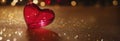 Banner with red glass heart on gold surface, festive background, warm blurred bokeh light. Valentine's Day Royalty Free Stock Photo