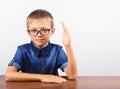 Banner Schoolboy in a blue shirt sitting at the table. Boy with glasses on white background Concept back to school