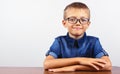 Banner Schoolboy in a blue shirt sitting at the table. Boy with glasses on white background Concept back to school