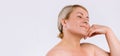 Banner. Senior woman with moisturized skin after cosmetic procedures smiles and looks to the side, gently touching the