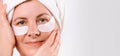 Banner. Senior woman with a towel on her head and eye patches looking at the camera against a white background with