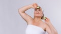 Banner. Senior woman with well-groomed skin and a bandage on her head looks upwards holding cucumber slices in her hands