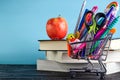 Banner of Shopping cart with school supply on a blue background with a stack of books and an apple with copy space. Back to school Royalty Free Stock Photo