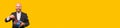 Banner size image of cheerful smiling bearded man in suit opening grift box over yellow background Royalty Free Stock Photo