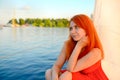 Summer landscape where is the horizon, blue river. and young woman in red dress dreamy sitting. Rest. Royalty Free Stock Photo