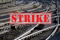 Banner with text STRIKE over lots of railroad tracks and switches, trade union concept for fair pay and working conditions in the