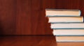 Banner with wide bookshelf and a stack of hardcovered books with bookmarks.