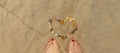 banner with women's feet onbeach and heart is laid out of pebbles. relaxing on beach, summer by sea Royalty Free Stock Photo