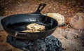 Bannock cooking over an open fire in fire pit.