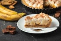 Banoffee cake with banana and caramel sauce filling sprinkled with grated dark chocolate on the black concrete background. English