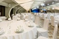 Banquet hall decorated in white with round served tables and stage for performance Royalty Free Stock Photo